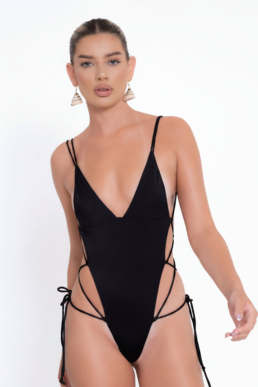 Woman wearing a black swimsuit with thin straps on a white background