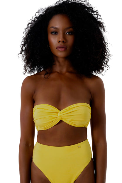 Woman wearing a yellow strapless bikini against a white background