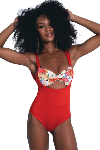 Woman wearing a red swimsuit with a colorful top against a light blue background